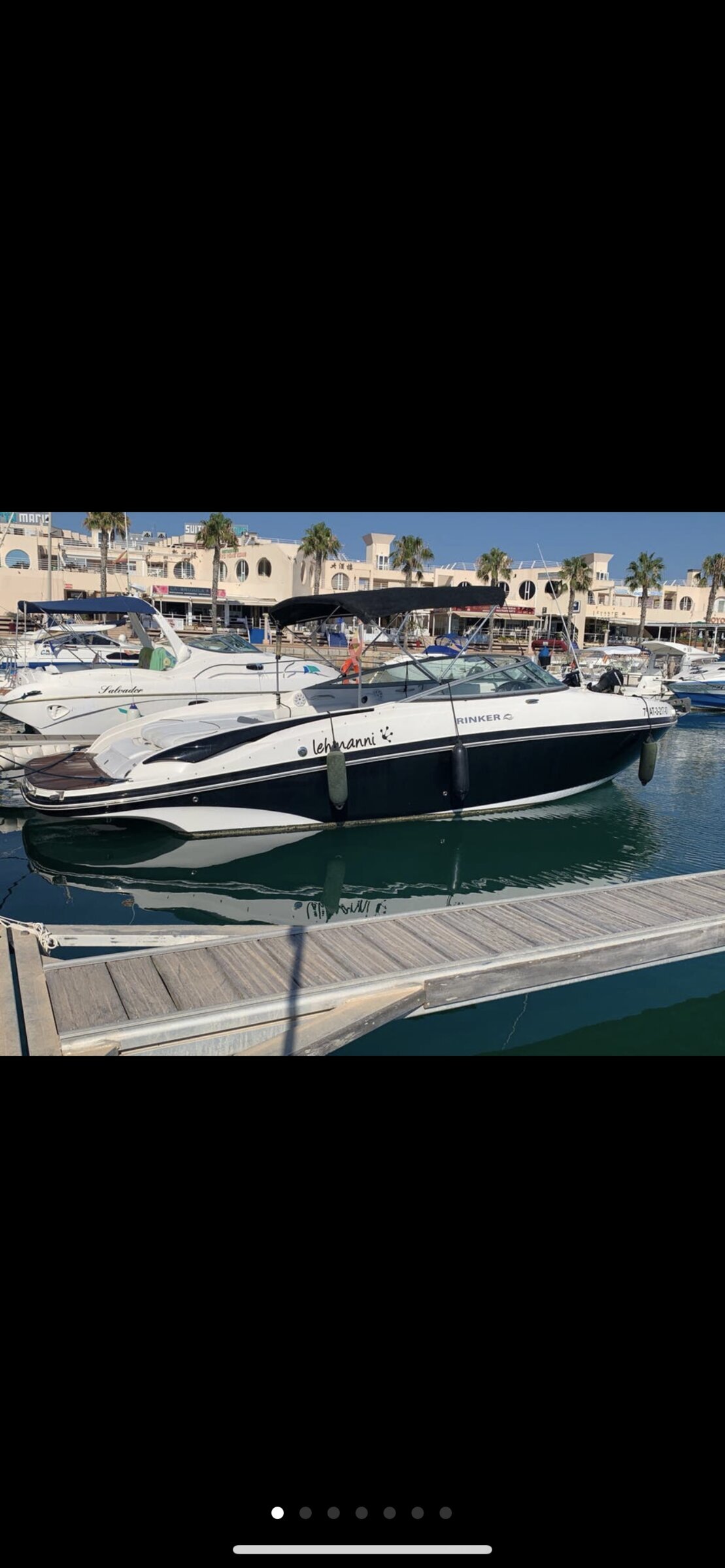 Bateau Rinker d’Arousa Charter amarré à la marina de Vilanova de Arousa avec palmiers en arrière-plan