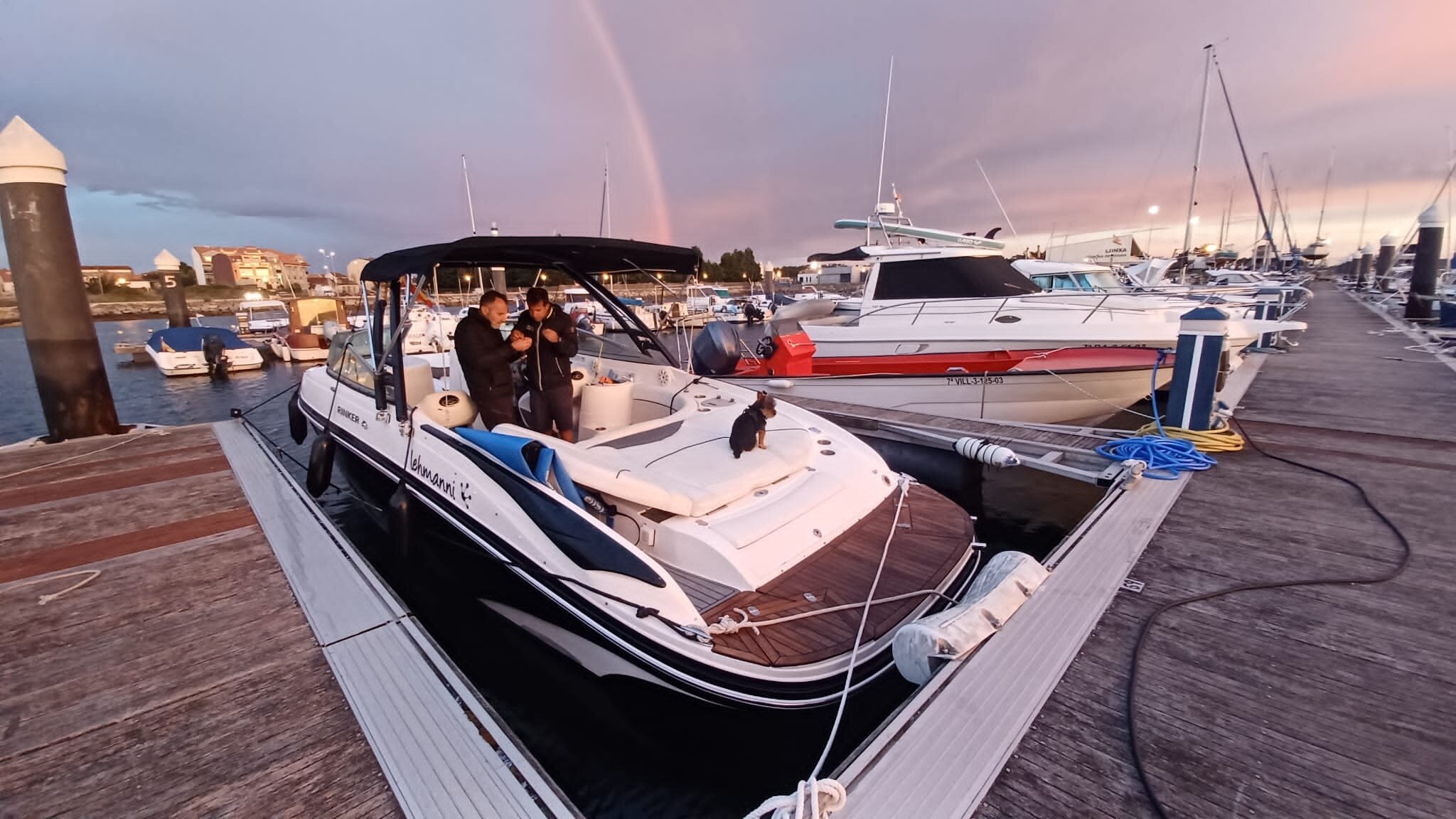 Coucher de soleil doré sur la marina de Vilanova de Arousa avec arc-en-ciel et bateaux amarrés